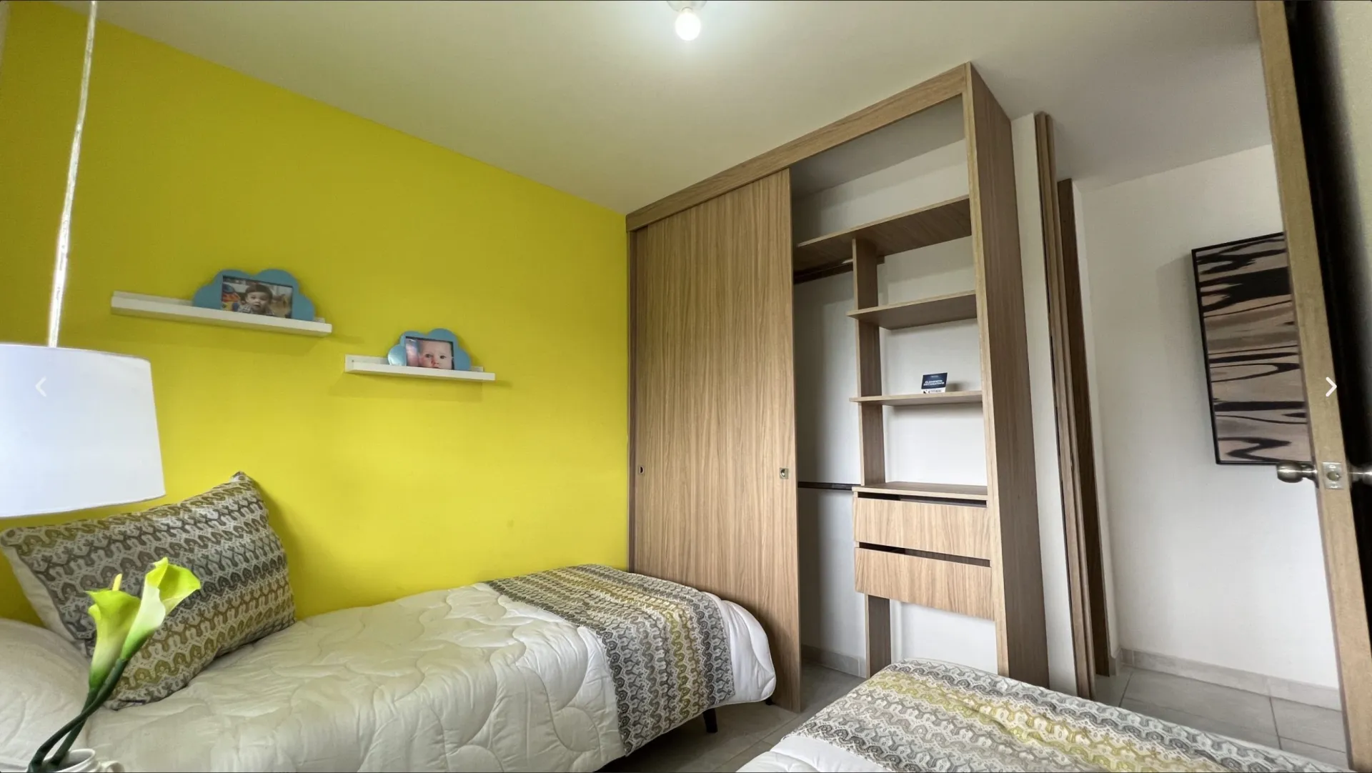 Alcoba auxiliar del apartamento modelo de San Juan de la Cuesta con dos camas sencillas y clóset en madera