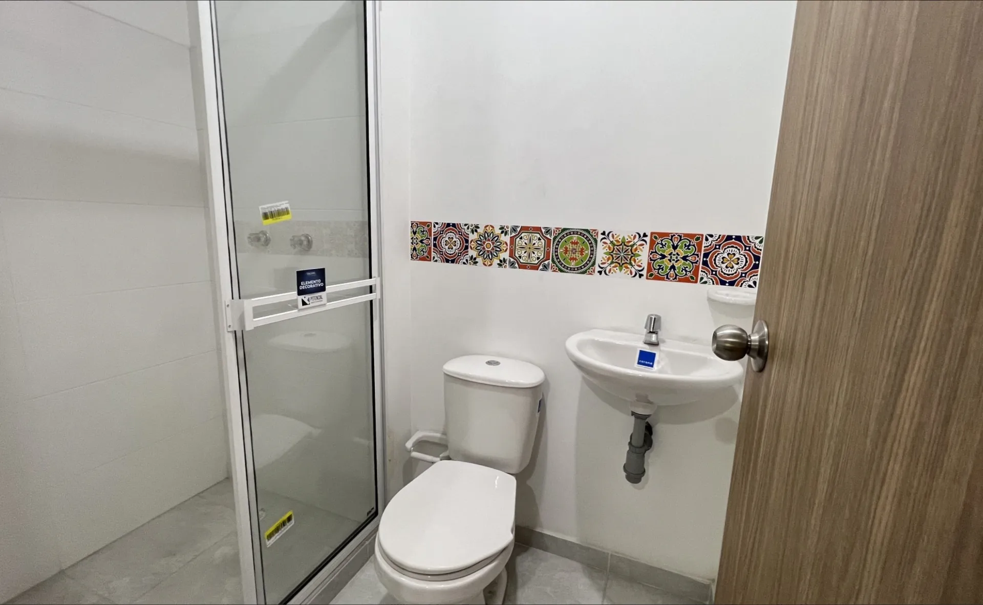 Baño del apartamento modelo de San Juan de la Cuesta con ducha, sanitario, lavamanos y cenefa decorativa